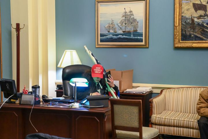 A supporter of US President Donald Trump sits at a desk after breaking into the US Capitol Building