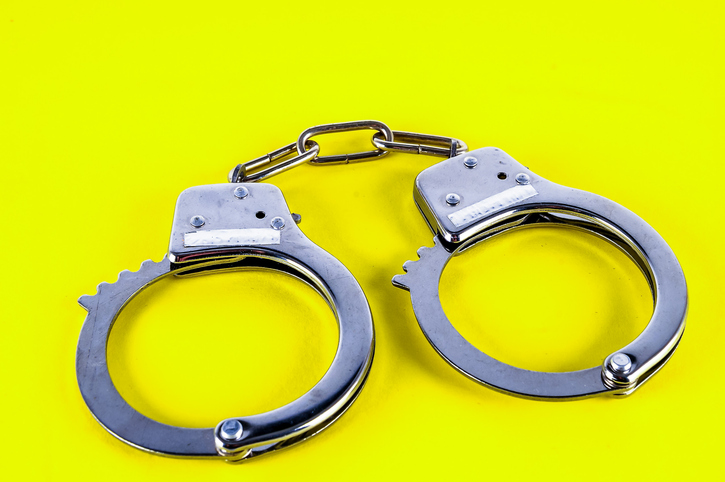 Two handcuffs are on a yellow background