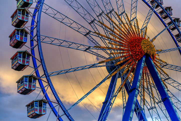 Ferris wheel illuminated at dusk with vibrant colors against a cloudy sky in a festive atmosphere