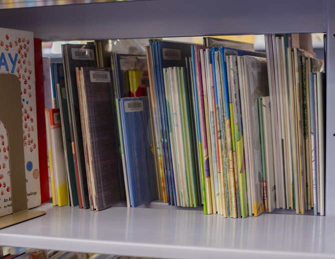 Children's books neatly organized on a white bookshelf in a library or classroom setting. Cleveland, Ohio, USA